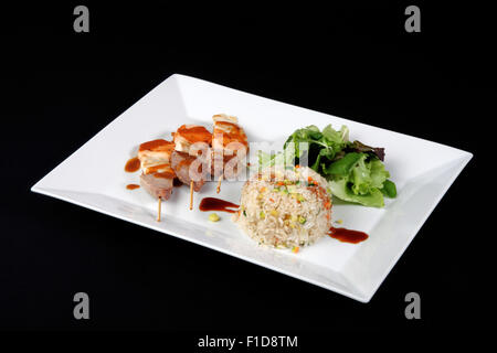 Menu di kebab con riso e verdure in piatto bianco su sfondo nero Foto Stock