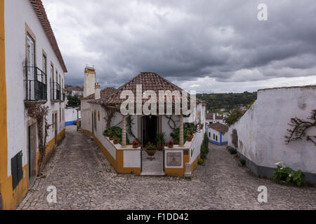 Casa Tradizionale tra le strette strade di ciottoli di Obidos village, con tradizionalmente case dipinte. Leiria, Portogallo. Foto Stock