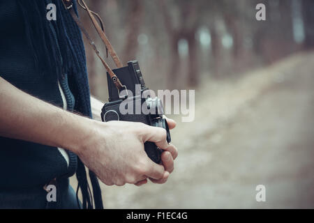 Vintage foto stilizzata delle mani del giovane fotografo con la vecchia telecamera. Foto Stock