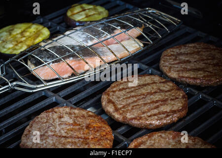 Hamburger fette, bistecca di salmone e melanzane alla griglia, rack, soft focus Foto Stock