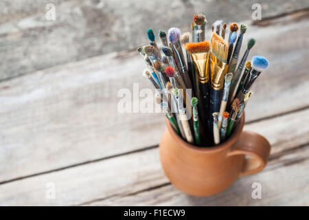 Usato pittore pennelli in una brocca da potters clay Foto Stock
