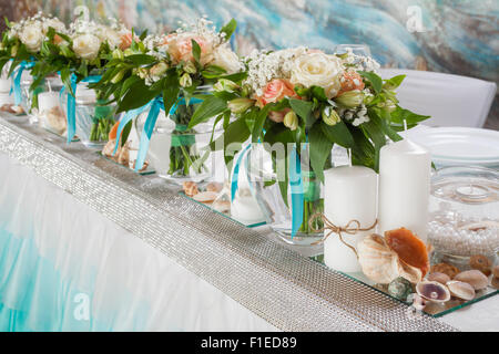 Splendido bouquet di rose e decorazioni su tavola in giorno di nozze. Foto Stock