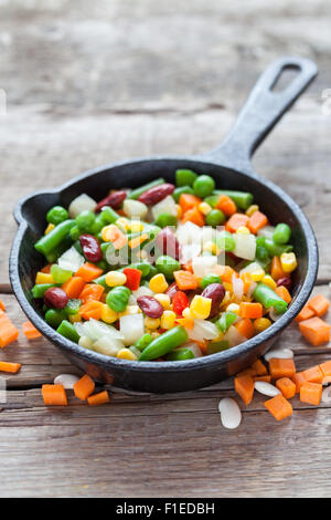 Verdure miste pasto nella vecchia padella e gli ingredienti su legno tavolo rustico. Foto Stock