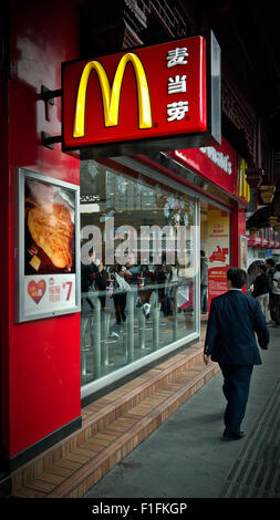 Un Edward Hopper immagine di stile di un McDonald's a Shanghai in Cina. Riflessioni e diners incorniciato da passer da e il Golden Arches Foto Stock