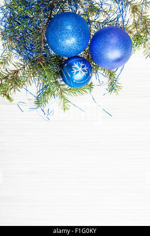 Auguri di Natale - Scheda di confine da tre blu Xmas baubles e ramo di albero su carta bianca sullo sfondo Foto Stock