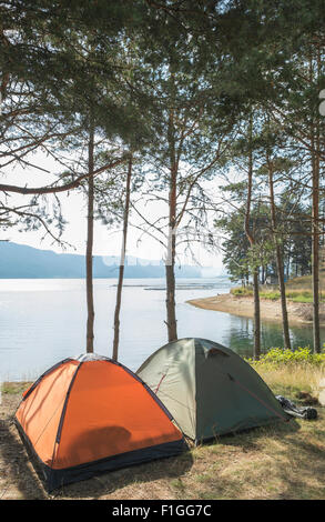 Le tende nella foresta di fronte lago di montagna Foto Stock