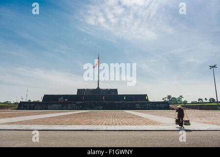 Hue cittadella Vietnam, vista di una donna venditore che porta i suoi prodotti oltre la torre della bandiera (Cot Co) vicino alla Cittadella imperiale di Hue, Costa Centrale, Vietnam. Foto Stock