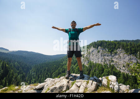 Uomo felice escursionista celebrando la libertà sul picco di montagna Foto Stock