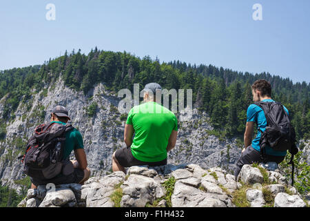 Felice escursionisti maschile seduto sul bordo di una molto alta rupe Foto Stock