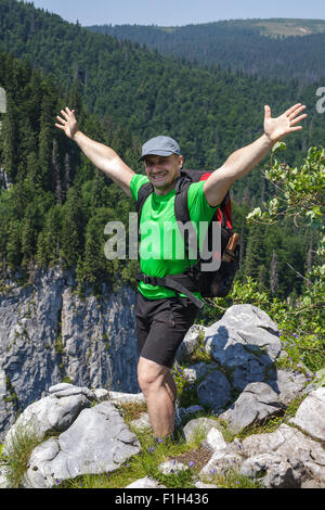 Uomo felice escursionista celebrando la libertà sul picco di montagna Foto Stock