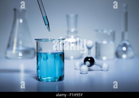 Ricerca di Chimica. Una pipetta trasferire il liquido in un becher e una sfera-e-stick modello molecolare Foto Stock