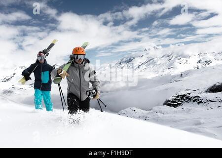 Gli uomini che trasportano gli sci sulla neve, Zermatt, Vallese, Svizzera Foto Stock