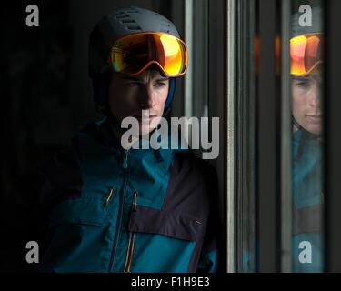 L'uomo sciatore che indossa gli occhiali e casco con segnale di rischio  biologico rendendo selfie mentre è seduto in un impianto di risalita cabina  in corrispondenza di inverno mountain resort Foto stock 