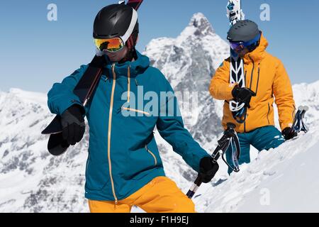 Due uomini il trasporto di sci nella neve, Zermatt, Vallese, Svizzera Foto Stock