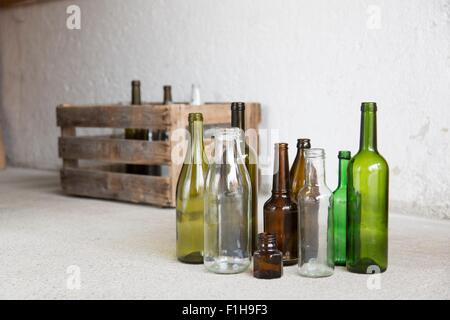 Varietà di bottiglie vuote e casse di legno in garage Foto Stock