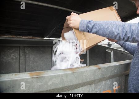 Ragazzo adolescente lo svuotamento dei rifiuti di carta al contenitore di riciclaggio Foto Stock