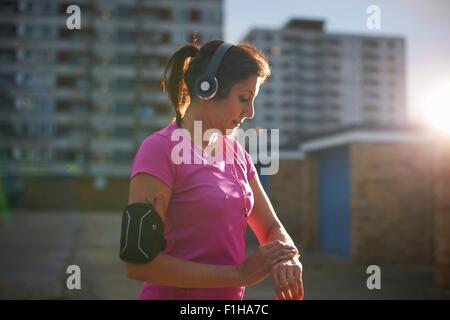 Femmina matura runner controllo orologio da polso al crepuscolo Foto Stock