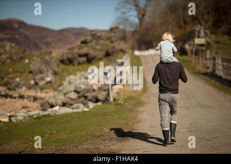 Padre figlio che porta sulle spalle, camminando sul percorso, vista posteriore Foto Stock