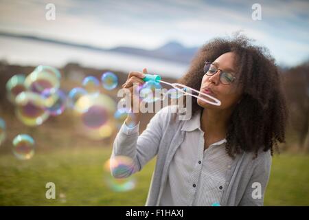 Metà donna adulta soffiare bolle Foto Stock