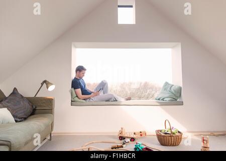 Metà uomo adulto seduto nel sedile finestra di lettura Foto Stock