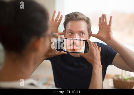 La donna lo smartphone di contenimento nella parte anteriore del la bocca dell'uomo, Foto Stock