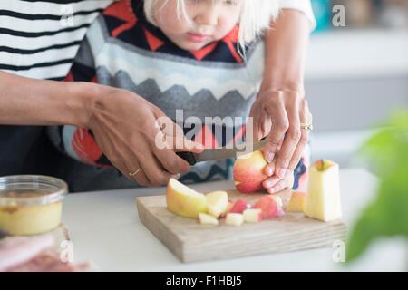 Madre aiutare figlio chop apple Foto Stock