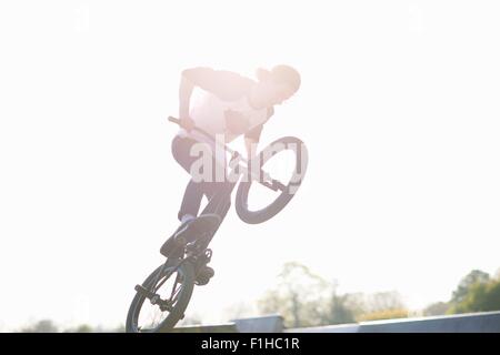 Giovane uomo facendo stunt su bmx a skatepark Foto Stock