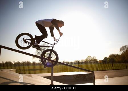 Giovane uomo facendo stunt su bmx a skatepark Foto Stock