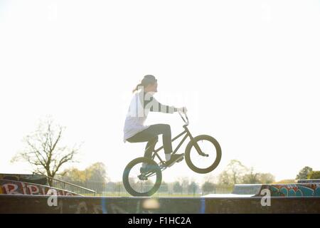 Giovane uomo facendo stunt su bmx a skatepark Foto Stock