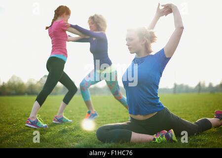 Tre donne che esercitano e stretching nel parco Foto Stock