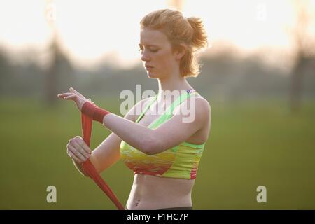 Ritratto di una donna l'applicazione di fascette a mano per i guantoni nel parco Foto Stock