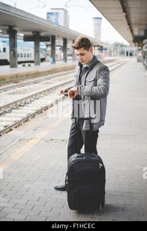 Ritratto di giovane imprenditore " commuter " controllo dell orologio da polso per il tempo alla stazione ferroviaria. Foto Stock