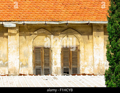 Le vecchie finestre con persiane di legno su una parete di colore giallo. Vintage sfondo : texture. Foto Stock