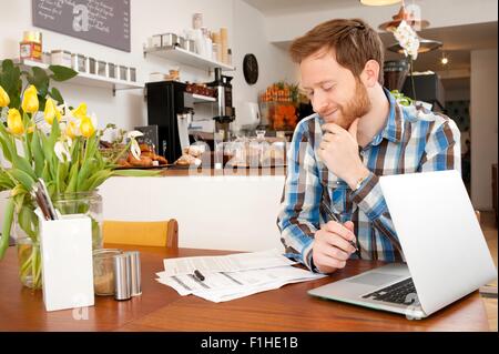 Maschio di riempimento del cliente nel modulo di domanda in cafe Foto Stock