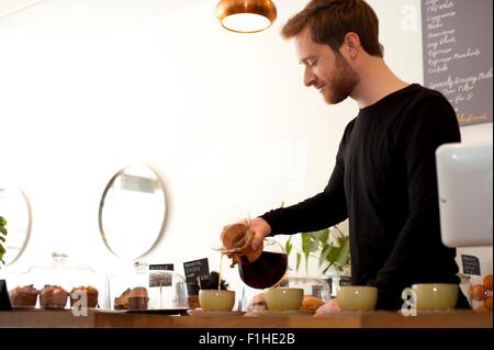 Cafe cameriere versando filtro nuovo caffè in tazze Foto Stock