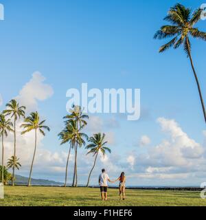 Vista posteriore della coppia giovane passeggiando vicino a spiaggia Kaaawa, Oahu, Hawaii, STATI UNITI D'AMERICA Foto Stock