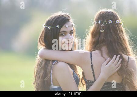 Vista posteriore del ritratto di due ragazze adolescenti che indossa daisy chain copricapo in posizione di parcheggio Foto Stock