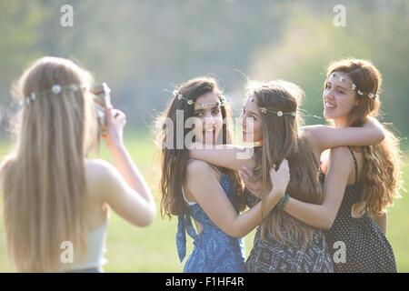 Ragazza adolescente fotografando tre amici utilizzando la fotocamera istantanea in posizione di parcheggio Foto Stock