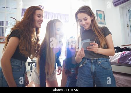 Quattro ragazze adolescenti guardando all'istante le fotografie in camera da letto Foto Stock