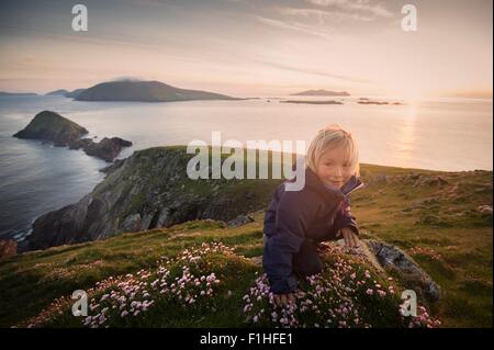 Ragazzo seduto sulla collina, Slea head, County Kerry, Irlanda Foto Stock