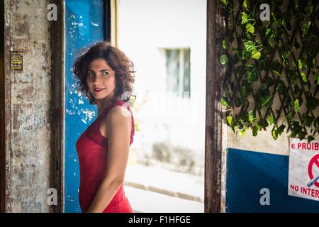 Modello di moda indossando abito rosso e sorridente Foto Stock
