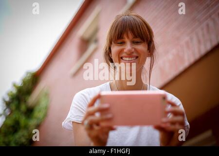 Bassa e vista di metà donna adulta utilizza lo smartphone, sorridente Foto Stock