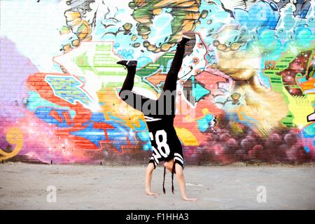 Giovani donne in handstand breakdance congelare contro graffiti Foto Stock