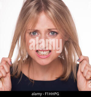 Donna bionda tirando i capelli con un senso di frustrazione Foto Stock