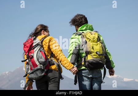 Vista posteriore di escursionismo coppia di fronte a Snow capped mountain, Vogogna, Provincia di Verbania, Piemonte, Italia Foto Stock