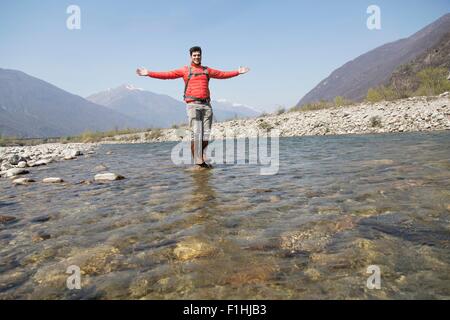 Ritratto di giovane maschio escursionista in piedi sul fiume Toce rock, Vogogna, Provincia di Verbania, Piemonte, Italia Foto Stock