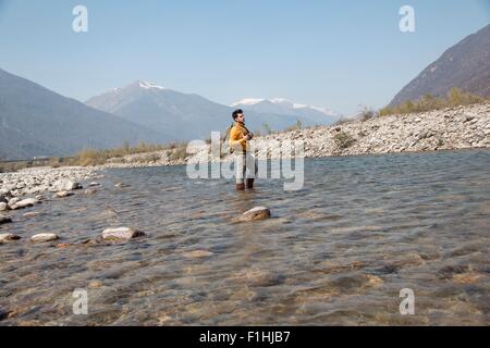 Giovane maschio escursionista guardando fuori dal fiume Toce, Vogogna, Provincia di Verbania, Piemonte, Italia Foto Stock