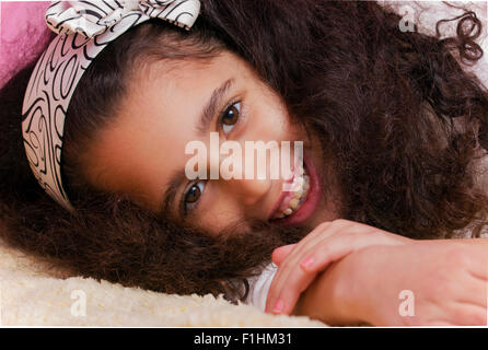 Bambino sorridente brunette swarthy ragazza distesa nel letto Foto Stock