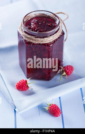 Organico in casa confettura di lamponi in vaso con frutti di bosco freschi sul tavolo di legno, fuoco selettivo Foto Stock