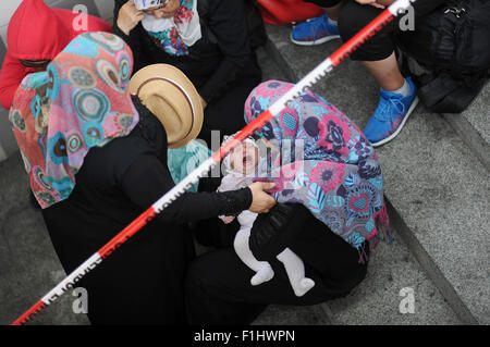 Rosenheim, Germania. 2 Sep, 2015. Una donna dalla Siria porta un bimbo che piange mentre si è in attesa di essere registrato presso un ufficio di registrazione, presso la stazione ferroviaria in Rosenheim, Germania, 2 settembre 2015. La polizia arrestati 50-60 rifugiati (soprattutto dalla Siria), in un treno in arrivo dall'Italia. Foto: ANDREAS GEBERT/dpa/Alamy Live News Foto Stock